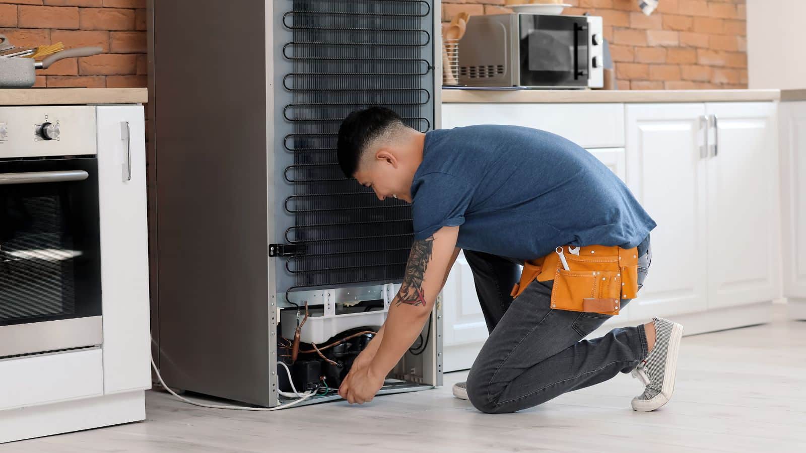 A man pulling out the part of refrigerator to fix.