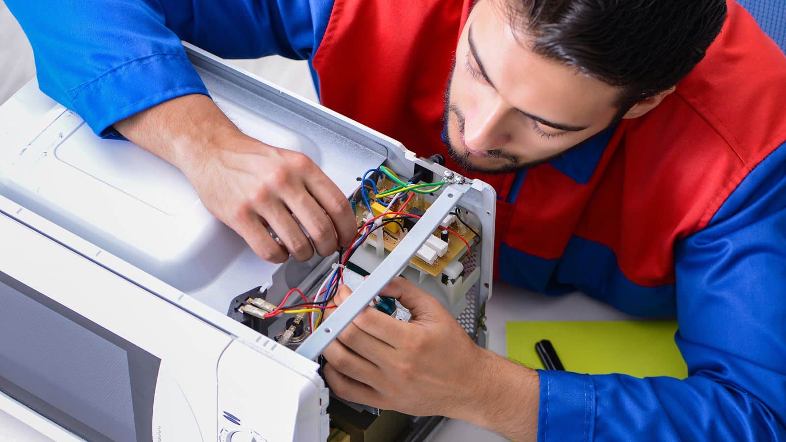 Young repairman fixing and repairing microwave oven.